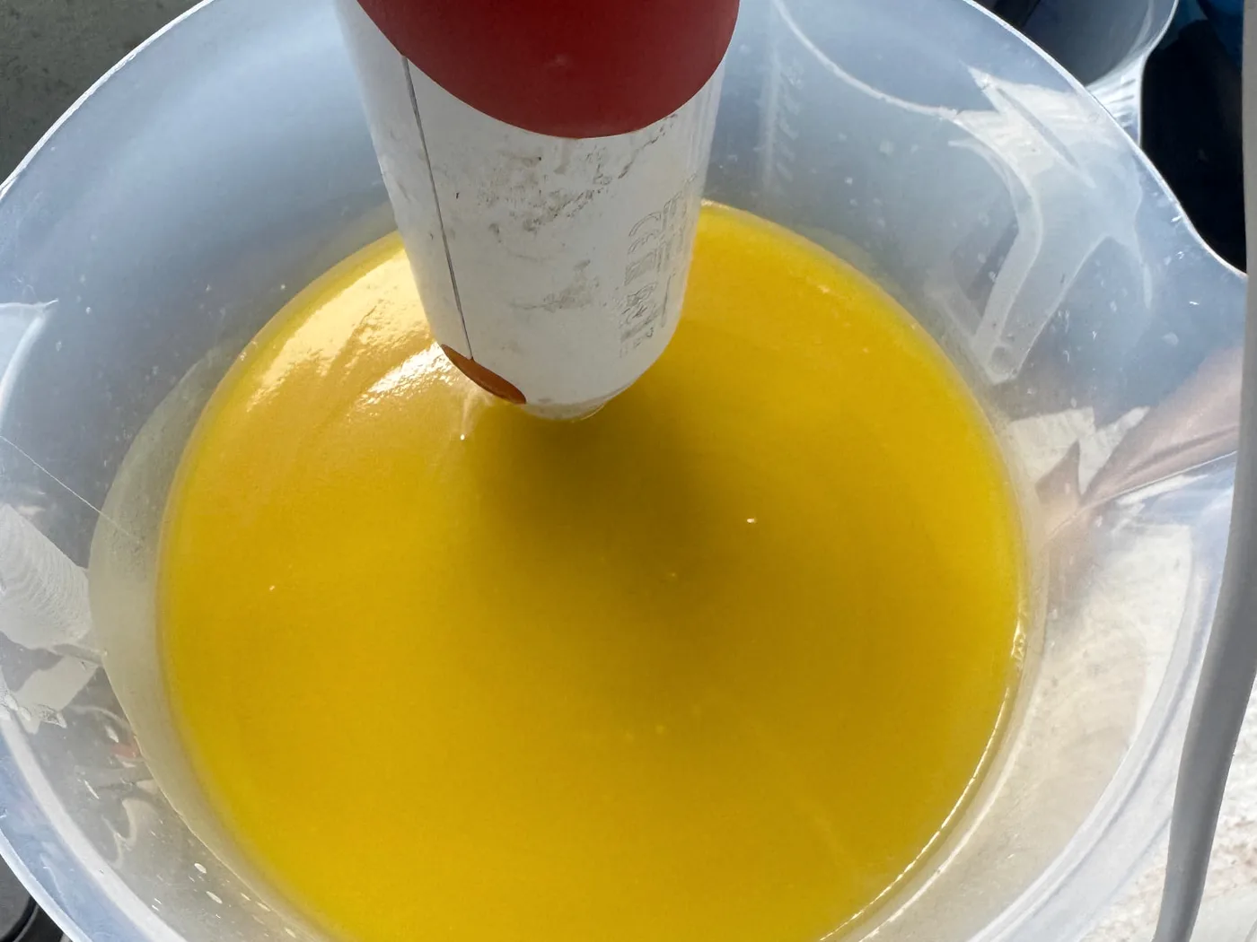Gesmolten oliën in een maatbeker, gemengd met een staafmixer